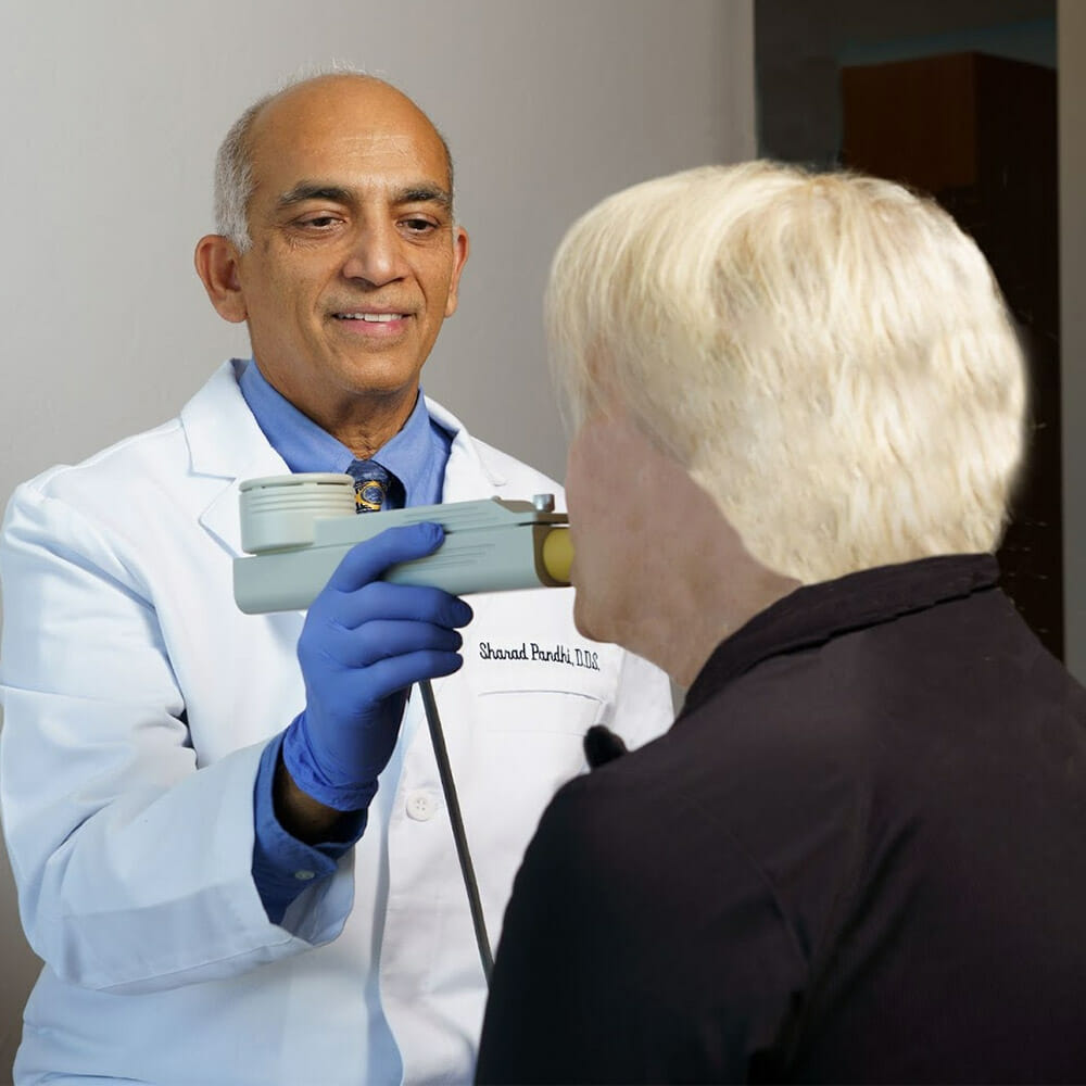 Dr. Sharad Pandhi uses a handheld diagnostic device on a patient during a medical evaluation