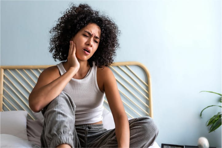 woman holding her jaw in pain