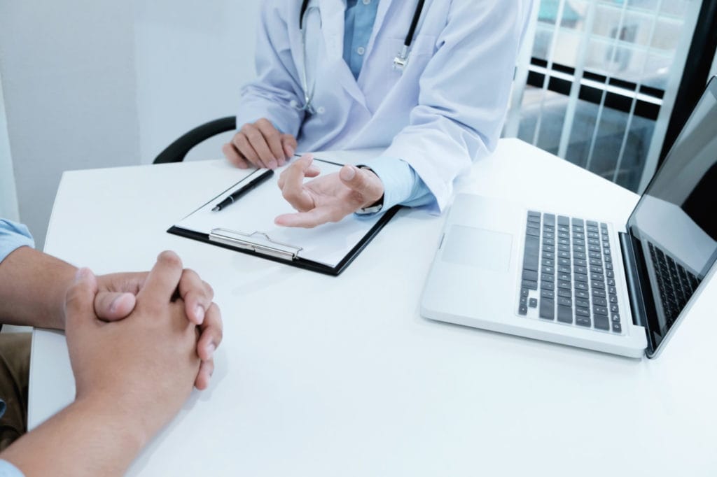 Doctor discussing diagnostic steps for sleep apnea with a patient at a medical consultation table.