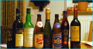 Row of various alcoholic beverages on a table, including wine and beer bottles
