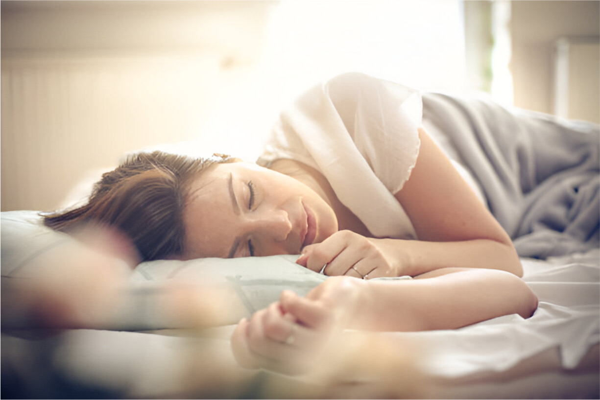 Woman peacefully sleeping in a softly lit bedroom during the day