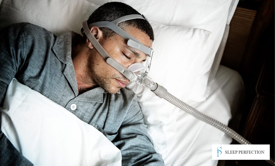 A man sleeps on his side wearing a CPAP mask to manage sleep apnea symptoms